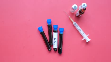 Hiv-blood-test-tube-and-syringe-on-red-background-,