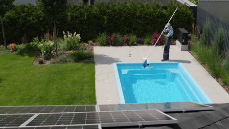 A-worker-removes-debris-from-a-pool-with-a-net.