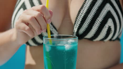 Attractive-Woman-in-bikini-shatters-ice-in-a-cocktail,-close-up-shot.