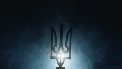 Coat-of-arms-of-Ukraine-in-the-fog,-illuminated-by-a-spotlight