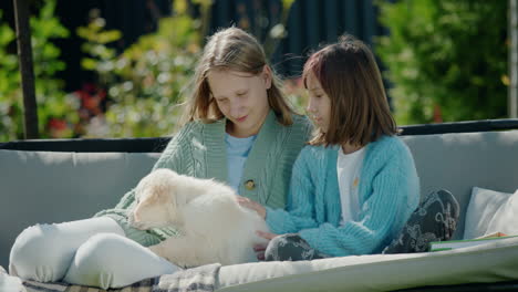 Two-girls-playing-with-a-puppy,-sitting-on-a-swing-in-the-backyard-of-the-house
