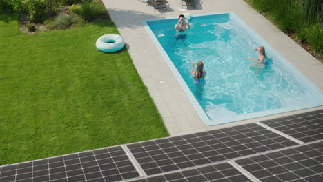 A-cheerful-family-plays-in-the-pool,-in-the-foreground-are-solar-power-panels-on-the-roof-of-their-house