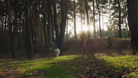 A-middle-aged-active-woman-runs-with-a-dog-through-the-forest---having-a-good-time-with-her-pet,-active-recreation