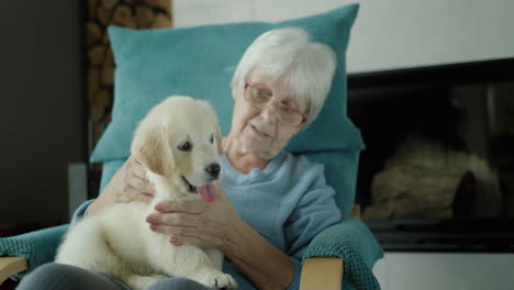 Happy-senior-woman-resting-in-chair-with-puppy-in-her-arms