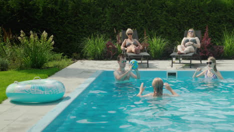 A-group-of-friends-play-ball-in-the-pool-and-relax-on-sun-loungers.-Have-fun-in-the-backyard-of-the-house