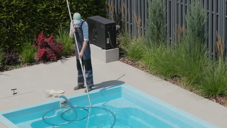 A-worker-cleans-a-swimming-pool-with-a-special-vacuum-cleaner.-Tilt-shot