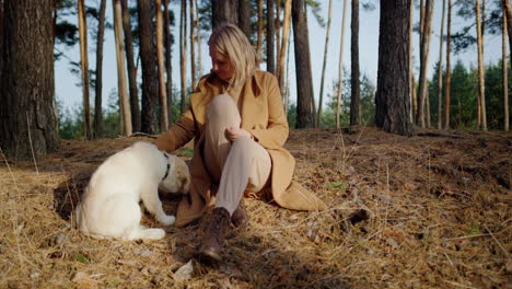 Cute-middle-aged-woman-relaxing-in-the-forest-with-a-golden-retriever-puppy