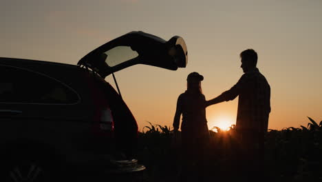 A-young-couple-is-arguing-in-front-of-a-broken-car.-The-car-is-parked-on-the-side-of-the-corn-field