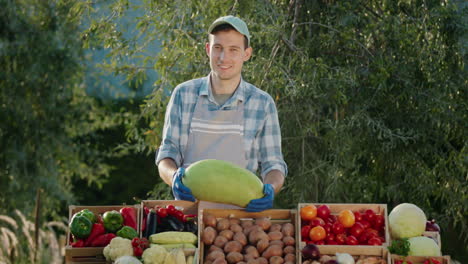 Portrait-of-a-seller-with-a-watermelon-in-his-hands.-Standing-behind-a-counter-at-a-farmers-market