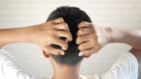 Teenage-boy-scratching-head-against-black-background