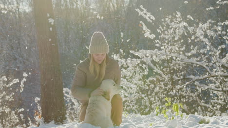A-young-woman-petting-her-dog-while-walking-together-in-a-picturesque-winter-park