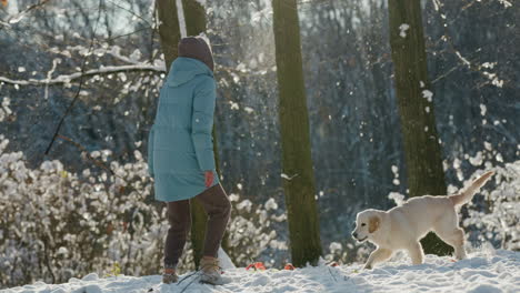 Happy-Woman-running-in-the-snow-with-her-dog,-having-a-good-time-on-a-walk-in-the-winter-forest