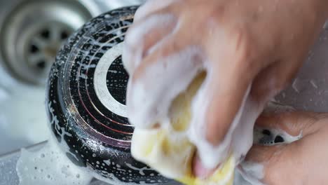 Cleaning-cooking-pan-with-a-sponge-,