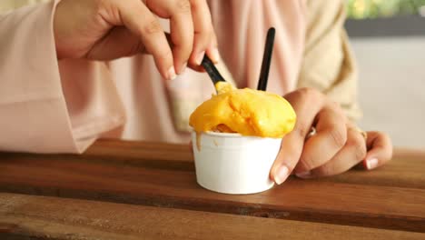 Frauen-Essen-Eis-Mit-Mangogeschmack-Auf-Dem-Tisch