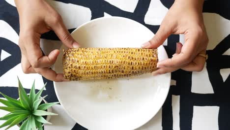 Women-holding-a-corn-cob-on-a-plate-,