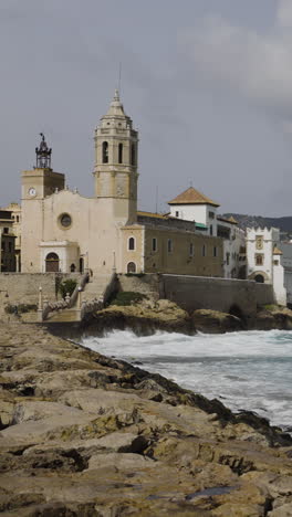 sea-church-and-buildings-in-sitges,-spain-in-vertical