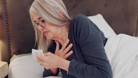 Senior-woman-blowing-her-nose-in-bed-with-tissues