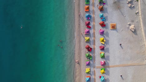 Beautiful-beach-with-colorful-umbrellas-on-sand-washed-by-clean-turquoise-seawater-in-Mediterranean,-Albania