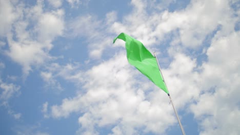 Low-angle-of-a-green-flag-on-the-beach-waving-in-slow-motion