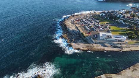 Bird's-Eye-View-Of-Car-And-Cycle-Park-At-The-Rocky-Seashore-Of-Clovelly-Beach-In-Sydney-City,-Australia