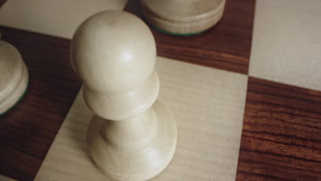 Tilt-down-Perspective-of-White-Queen-and-Pawn-Chess-Piece-in-Position-for-Battle,-Closeup