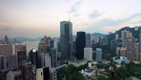 Aerial-view,-Hong-Kong-central-district,-skyscrapers-and-buildings-under-cloudy-sky-in-twilight,-pull-back-drone-shot