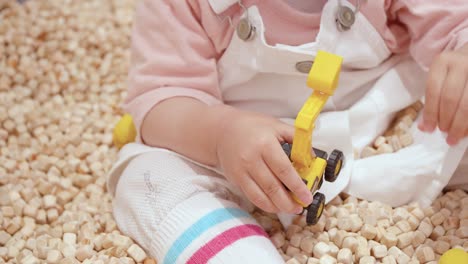 Cropped-Portrait-Of-A-Female-Toddler-Playing-Mini-Tractor-Toy