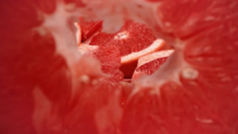 Closeup-pull-away-through-the-center-of-grapefruit-slice-as-it-falls-over-product-food-video-4k