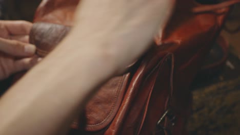 A-Woman's-Hands-Applying-A-Polishing-Wax-To-Her-Leather-Vintage-Backpack-Using-A-Clean-Sponge---Closeup-Shot