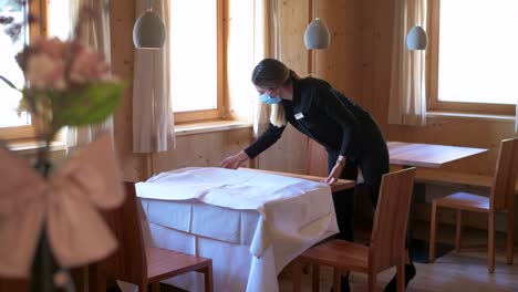 The-waitress-with-a-face-mask-takes-the-tablecloth-from-the-table