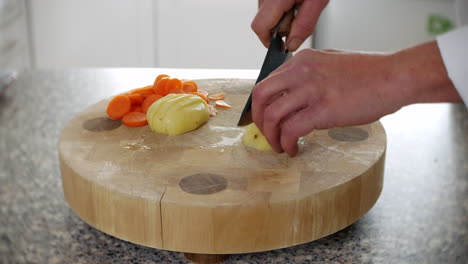 A-chef-is-chopping-a-potato-into-wedges-for-chips-and-fries-in-a-kitchen-on-a-chopping-board-with-a-knife