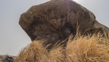A-zooming-in-time-lapse-of-a-large-granite-bolder-in-Africa-with-with-blowing-through-the-grass