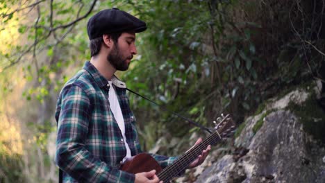 Static-footage-with-blurry-nature-background-of-an-inspire-musician-playing-a-song-with-accoustic-guitar