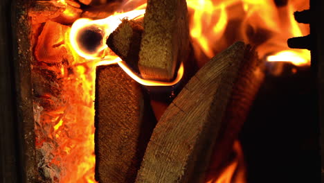 Fiery-flame-of-burning-firewood-in-domestic-fireplace,-vertical-close-up-view