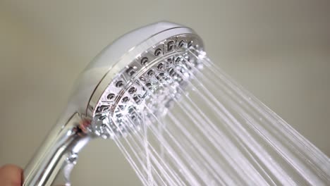 Male-hand-flips-a-switch-on-the-running-shower-head-to-switch-between-the-different-jet-settings