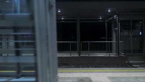 Passenger-view-from-inside-of-the-train-passing-train-station-at-night