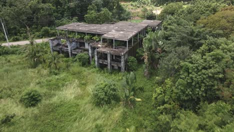 Aerial-fast-dolly-shot-of-derelict-unfinished-small-house-,-resort-building-on-a-tropical-island-with-palm-trees