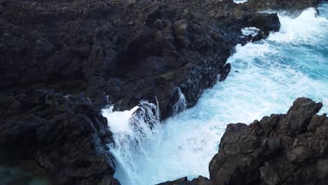 A-shot-of-the-waves-crashing-on-a-small-black-volcanic-rock-cliff