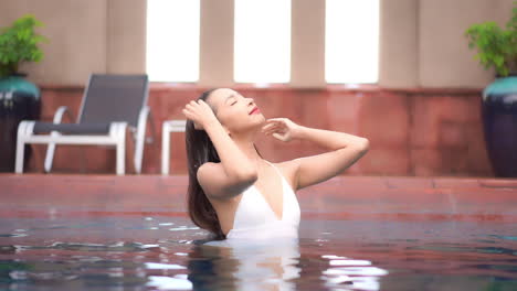 Junge-Sexy-Asiatische-Frau-Streichelt-Nasses-Haar-Nach-Dem-Schwimmen-Im-Pool,-Zeitlupe
