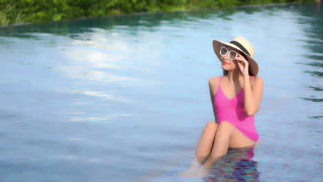 Lonely-Happy-Sexy-Young-Asian-Woman-in-Swimming-Pool-With-Summer-Hat,-Sunglasses-Enjoying-in-Sunny-Summer-Day-on-Her-Vacation,-Full-Frame-Slow-Motion