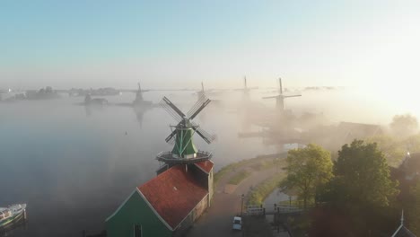 Die-Drohne-Fliegt-An-Einem-Nebligen-Morgen-In-Der-Zaanse-Schans-In-Der-Nähe-Einer-Windmühle-In-Den-Niederlanden-Vorwärts,-Filmische-Drohnenaufnahme-In-4K