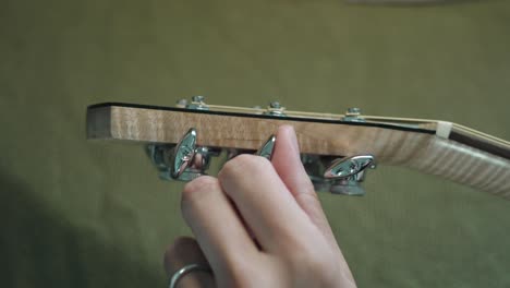 Guitarist-Tuning-The-Acoustic-Guitar-By-Turning-The-Machine-Heads-Or-Tuning-Pegs-On-The-Headstock
