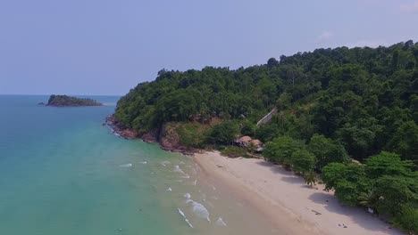 Tropical-Island-drone-ascending-shot-with-lush-green-rain-forest-and-tropical-palm-trees-with-white-sand-beach-and-rocky-coastline