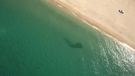 High-Aerial-Rotational-Drone-Fly-Over-Footage-of-green-emerald-ocean-with-swarm-of-baitfish-at-Cabo-San-Lucas,-Mexico