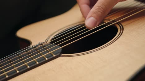 Tuning-An-Acoustic-Guitar-By-Plucking-The-Strings---close-up