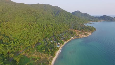 Tropical-Island-drone-spin-rotation-shot-with-lush-green-rain-forest-and-tropical-palm-trees-with-white-sand-beach-and-rocky-coastline