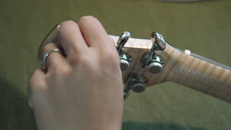 Man-Checking-And-Tuning-The-Guitar-By-Turning-The-Machine-Heads-Of-An-Acoustic-Guitar