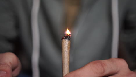 Close-up-of-hands-lighting-a-hash-joint-with-floating-flame,-bokeh