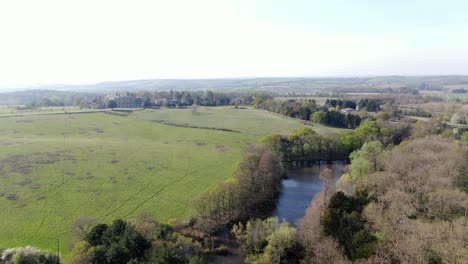 Luftaufnahme-Eines-Großen-Sees-Auf-Einem-Bewaldeten-Hall-Estate-Lake-Mit-Einem-Haus-Im-Hintergrund,-England,-Essex
