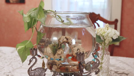 Close-up-footage-of-an-ornate-fish-bowl-planter-with-goldfish-swimming-about-in-the-bowl